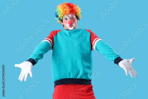 Portrait of shrugging clown on blue background. April Fool s day celebration