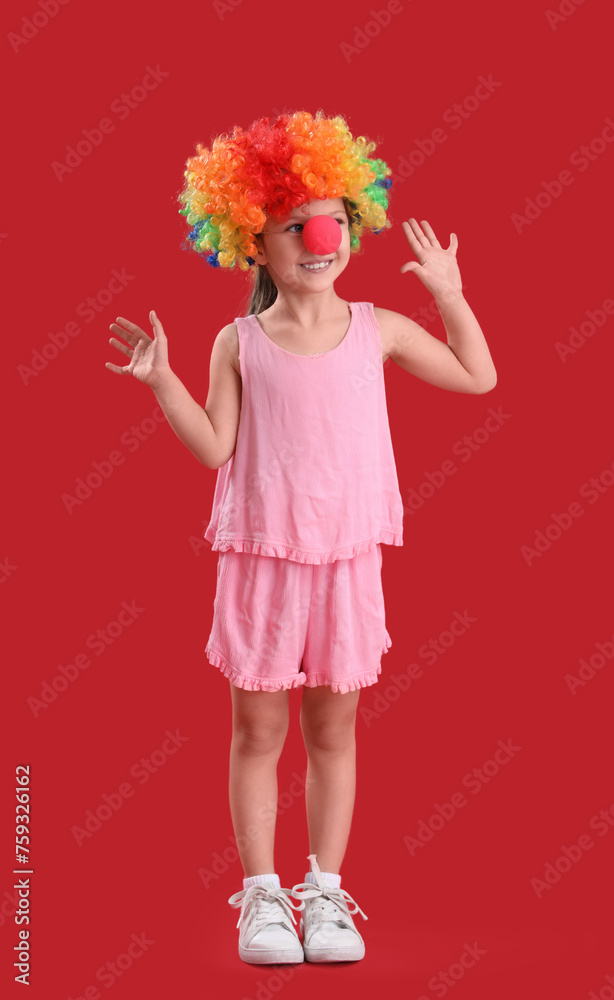Cute little girl with colorful clown wig on red background. April Fool's Day celebration Cute little girl with colorful clown wig on red background. April Fool's Day celebration