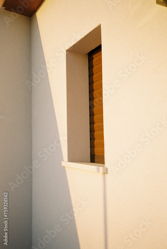 Angular view of sole ocher window in light yellow wall and shadow
