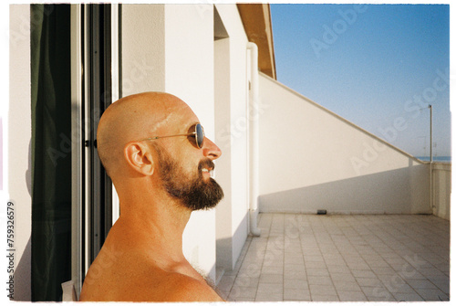 Portrait of bald man wearing sunglasses sunbathing and smiling photo