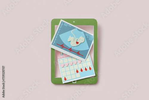 Paper tablet with ultrasound baby scan and female calendar on screen