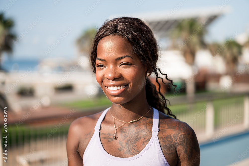 © Igor Kardasov/Stocksy - Smiling black woman in sportswear on street on sunny day