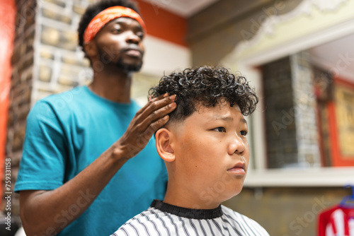 barber cutting the hair of a young asian boy photo