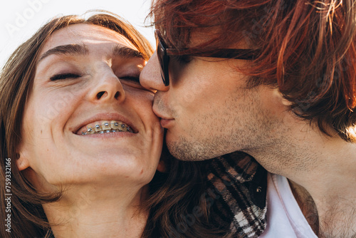 A boyfriend kissing his Happy girlfriend with braces photo