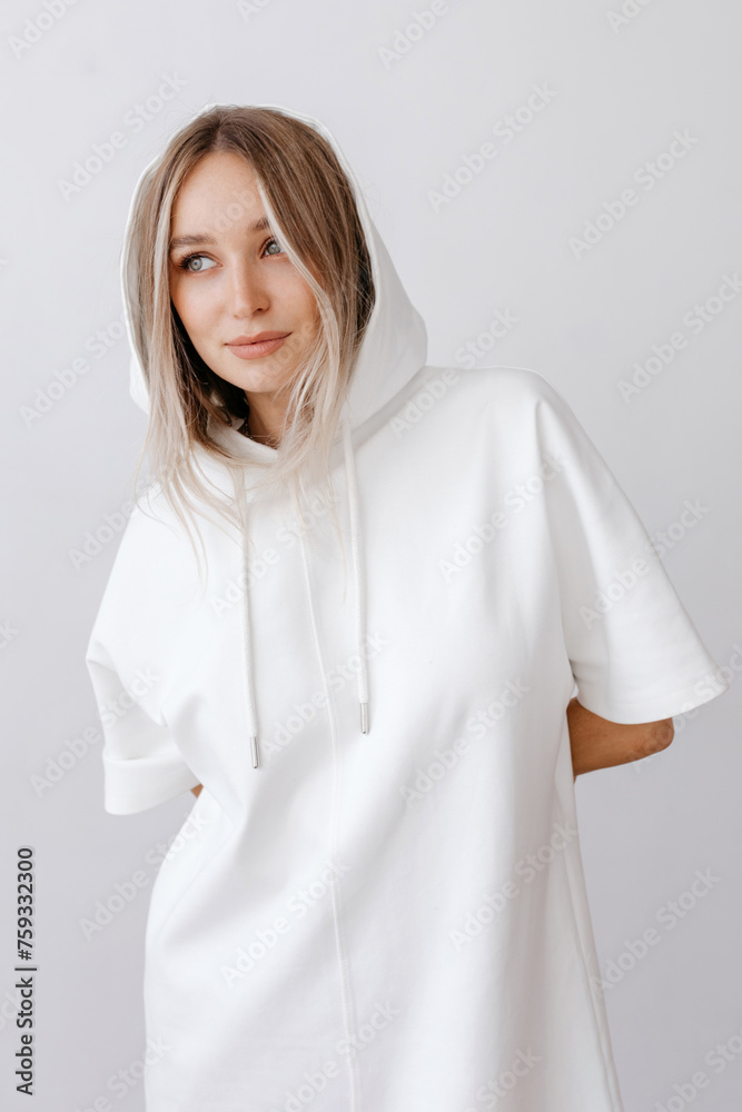 Happy young woman in hoodie standing with hands behind Happy young woman in hoodie standing with hands behind