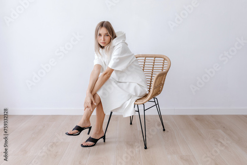 Young woman in hoodie sitting with crossed hands on leg photo