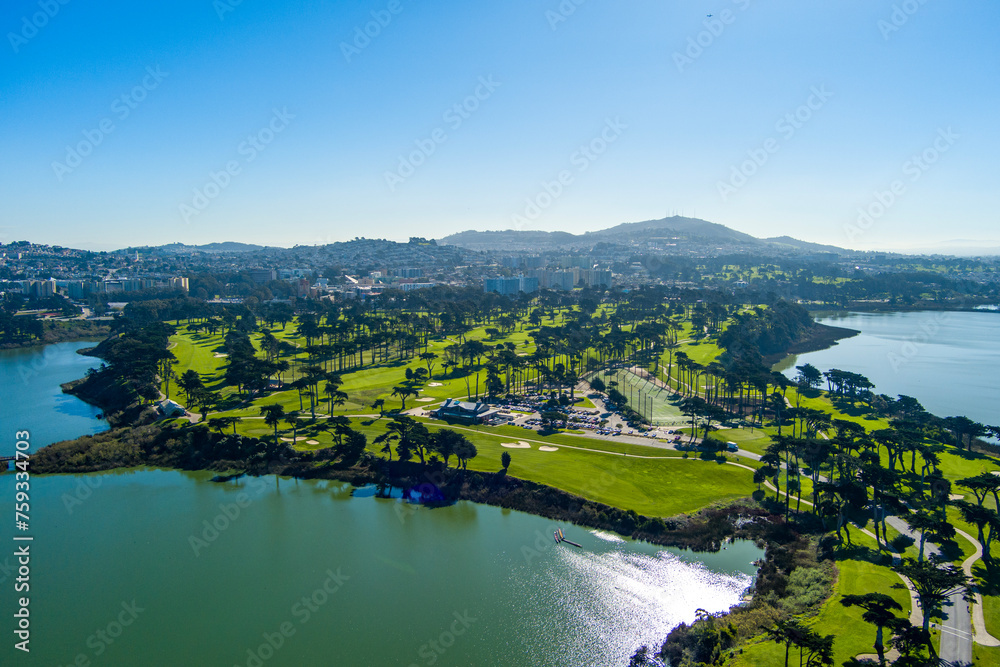 aerial shot of a beautiful spring landscape at Lake Merced with blue lake water and lush green trees, grass and plants and blue sky in San Francisco California USA