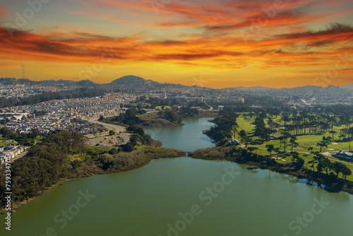 aerial shot of a beautiful spring landscape at Lake Merced with blue lake water and lush green trees  grass and plants at sunset in San Francisco California USA