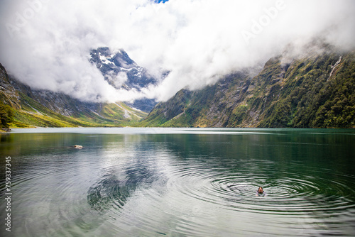 pretty girl in a swimsuit takes a bath in famous lake marian surrounded with mountains lake in fiordland national park near milford sound, new zealand south island photo