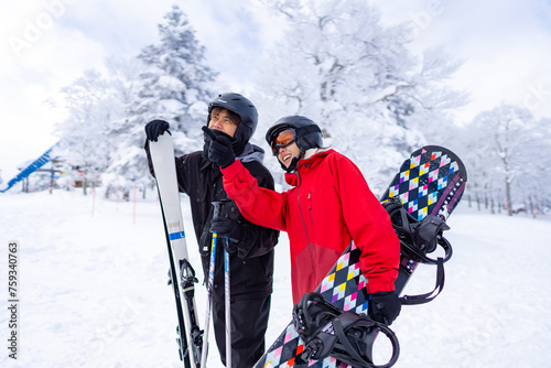 Happy Asian people enjoy outdoor active lifestyle winter extreme sport training on holiday vacation. Man and woman athlete practicing freeride snowboarding and ski at ski resort on snowy mountain.