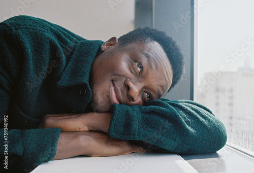 A portrait of a young man leaning by the window