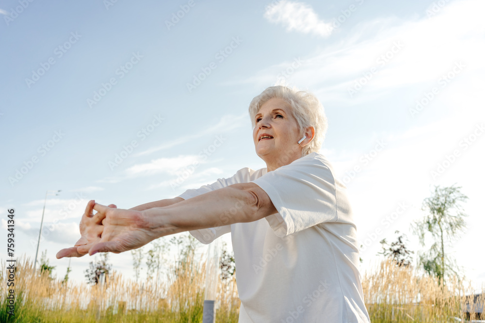 Pensioner female doing gymnastics against blue sky