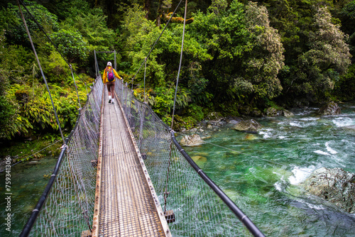 hiker crossing a rushing river in fiordland national park, new zealand south island, hiking trail to lake marian