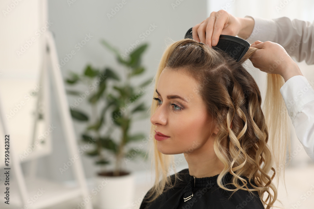 Fototapeta premium Hair styling. Hairdresser combing woman's hair in salon, closeup. Space for text
