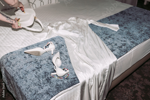 Cozy bed with wedding dress and high heels in hotel bedroom photo
