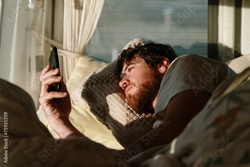 Man checking phone in bed photo