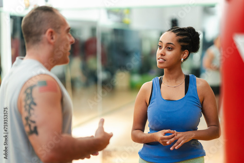 Smiling Ethiopian woman talking to trainer in gym photo