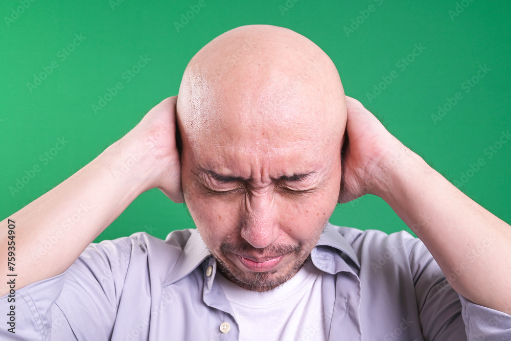 Young man stressed by noise, closing ears with both hands isolated green background. Young man stressed by noise, closing ears with both hands isolated green background.