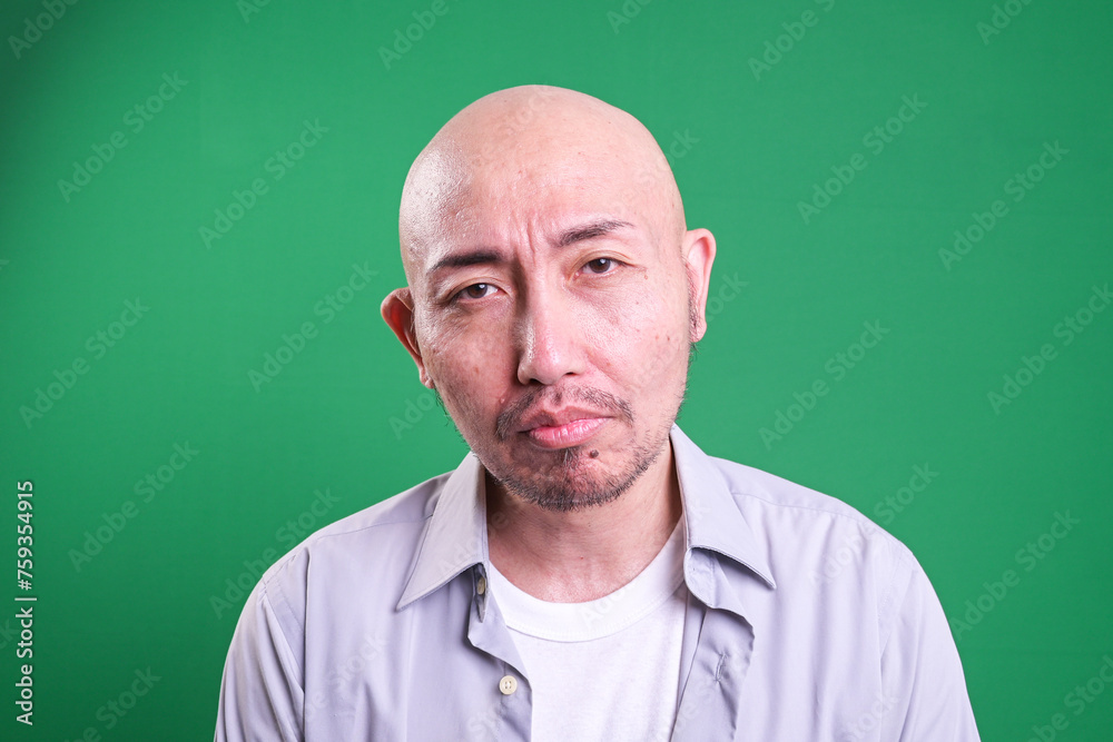 Obraz premium Portrait of Sad Asian Man Isolated on Green Background. Mental Health Concept. 