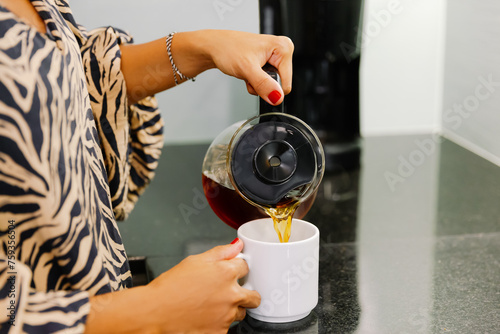 Close-up of a woman pouring a cup of coffee photo