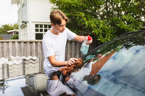 Teen cleaning vehicle from dirt outdoors photo