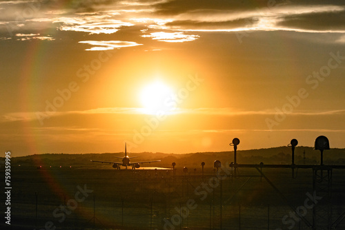 A passenger plane is preparing to take off on the runway at sunset photo