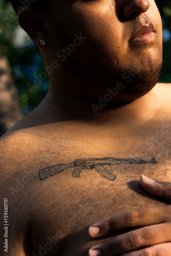Detail of AK47 shotgun tattoo on the chest of a plus size black boy. photo