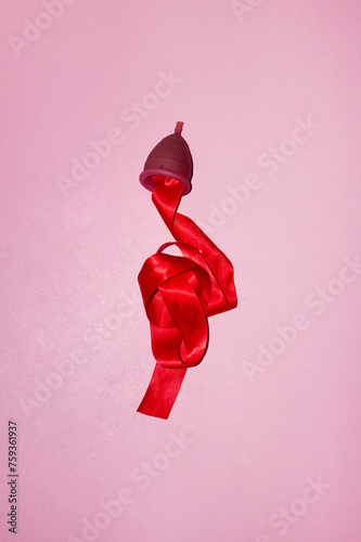 Conceptual photo of period / menstrual cup & red silk ribbon as blood photo