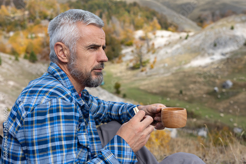 man drinking coffee in mountains photo