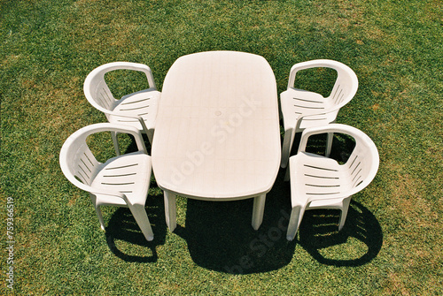Top view of a white plastic table and four chairs on a lawn background photo