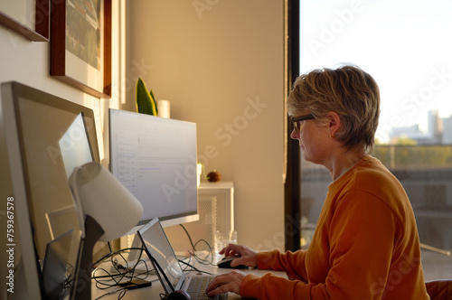 Woman working from home using multi screen set up photo