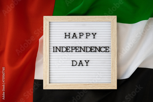 HAPPY INDEPENDENCE DAY text frame on United Arab Emirates waving flag made from silk material. Commemoration Day Muslim Public holiday celebration background. The National Flag of UAE