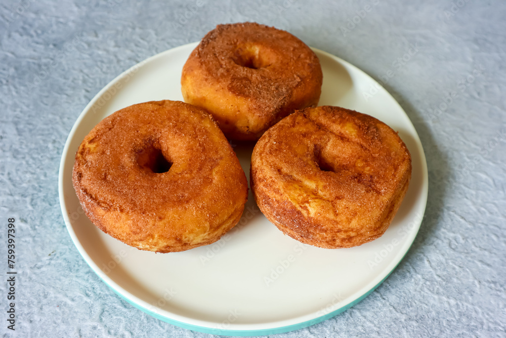 Sweet donuts with chocolate powder on a plate, close up