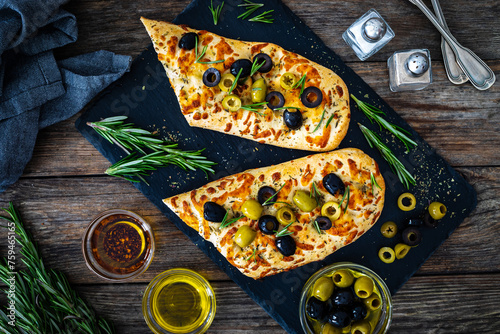 Focaccia alle olive - baked sandwich with green and black olives and rosemary on wooden background
 photo