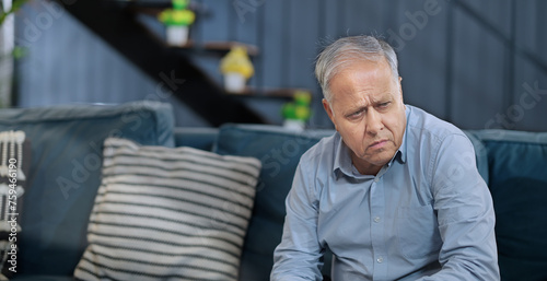Asian India retired old elder gen x tired upset sad man sitting alone sofa couch feel bad indoor home Indian aged older adult tense lost male think lonely suffer ill sick health issue house photo
