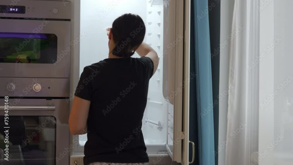 woman housewife cleaning built-in refrigerator inside in kitchen woman housewife cleaning built-in refrigerator inside in kitchen