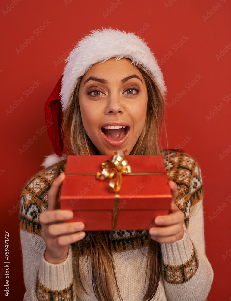 Excited woman, portrait and Christmas with gift for festive season or December holiday on a red studio background. Happy female person, surprise or wow with hat for special present, prize or offer Excited woman, portrait and Christmas with gift for festive season or December holiday on a red studio background. Happy female person, surprise or wow with hat for special present, prize or offer