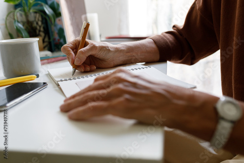 Senior person writing in a notebook photo