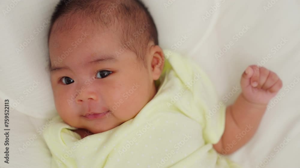 Close up of asian young newborn baby in a nursery lying on the bed. Parent looking at infant. Talk, touch, enhance child's development. parenthood, childhood, maternity, children, motherhood. Close up of asian young newborn baby in a nursery lying on the bed. Parent looking at infant. Talk, touch, enhance child's development. parenthood, childhood, maternity, children, motherhood.