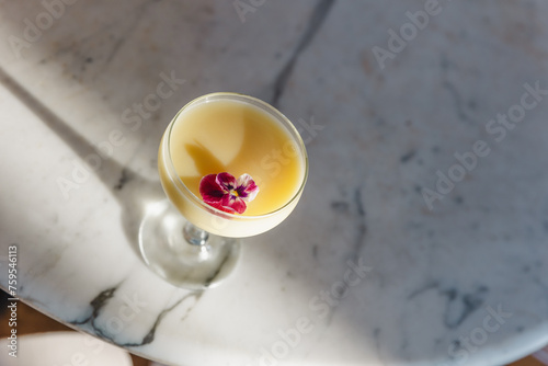 Fruit and acholc mix in a glass with flower decoration, white marble table, drink under sunlight