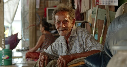 A smiling Asian man who is an elderly ragpicker or has a career collecting garbage and selling it, live in a slum village photo