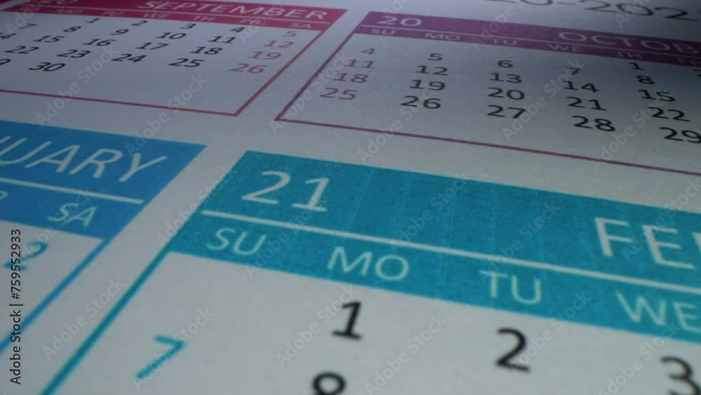 Close-up of two male hands tearing off the wall calendar September page 2023 followed by the next one with marked Halloween date on it Close-up of two male hands tearing off the wall calendar September page 2023 followed by the next one with marked Halloween date on it