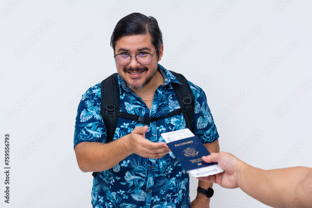 Smiling and friendly male traveler in a tropical shirt receiving a boarding pass placed inside his US passport before a trip. Isolated on white.