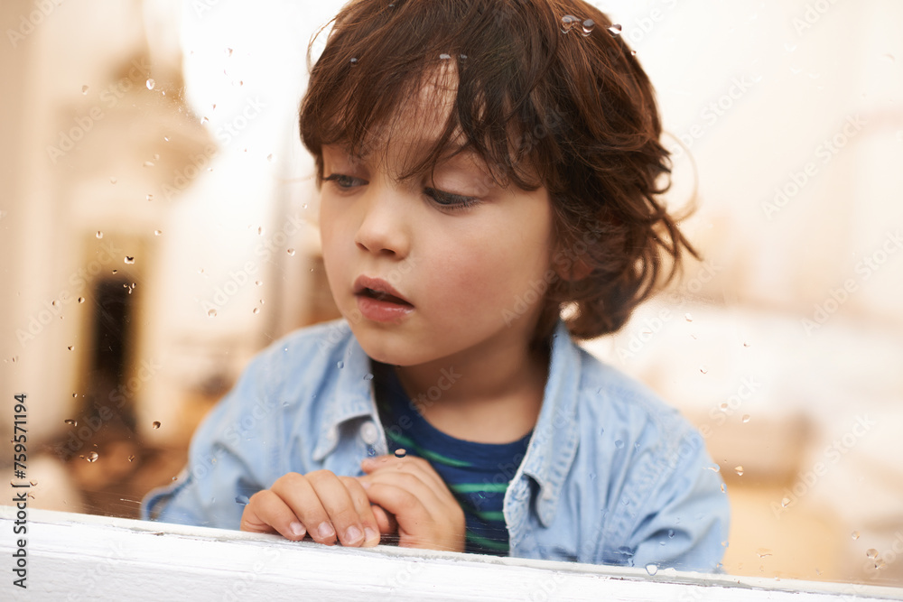 Window, sitting and boy in home for rain, bored or lonely for disappointed or sad for season outdoor. Young child or kid and watching weather in house for cold and wait for play for childhood Window, sitting and boy in home for rain, bored or lonely for disappointed or sad for season outdoor. Young child or kid and watching weather in house for cold and wait for play for childhood
