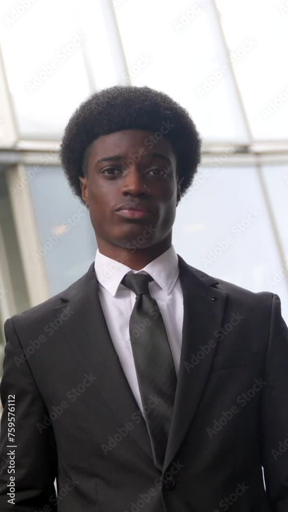 Low angle view portrait of a young busy african businessman talking to the mobile while commuting in the city Low angle view portrait of a young busy african businessman talking to the mobile while commuting in the city