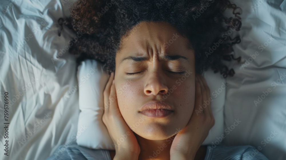 Woman lying in bed covering ears, frustrated by insomnia or external noise. Woman lying in bed covering ears, frustrated by insomnia or external noise.