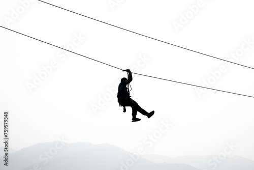 Silhouette of the person on the zip line in the sky