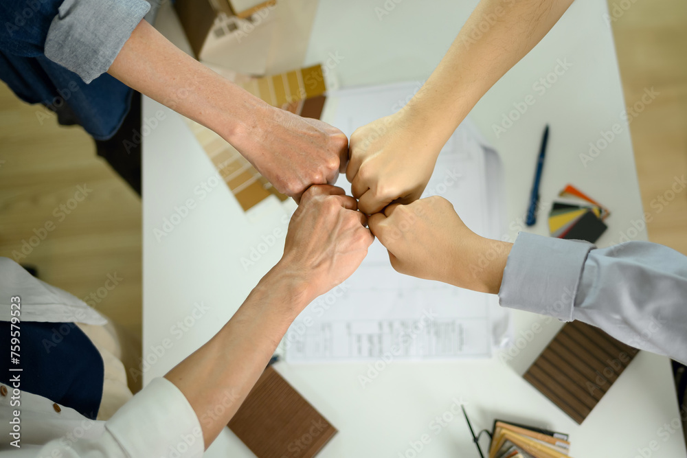 Overhead view architects joining their hands together in unity and teamwork