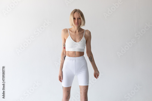 Blonde girl posing on a white background in a top and leggings © kanashkin