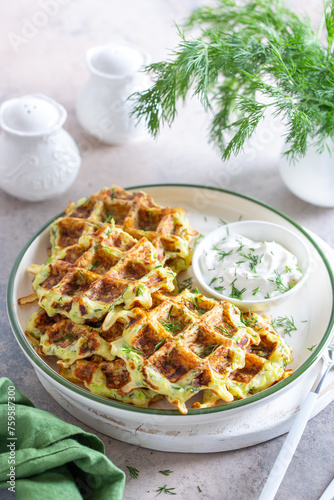 Zucchini waffles with herbs on a plate with sour cream, selective focus